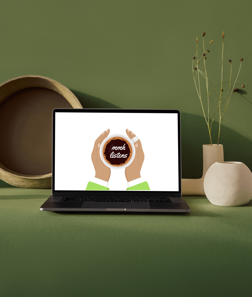 A laptop sits on a green table with MMH logo on screen.